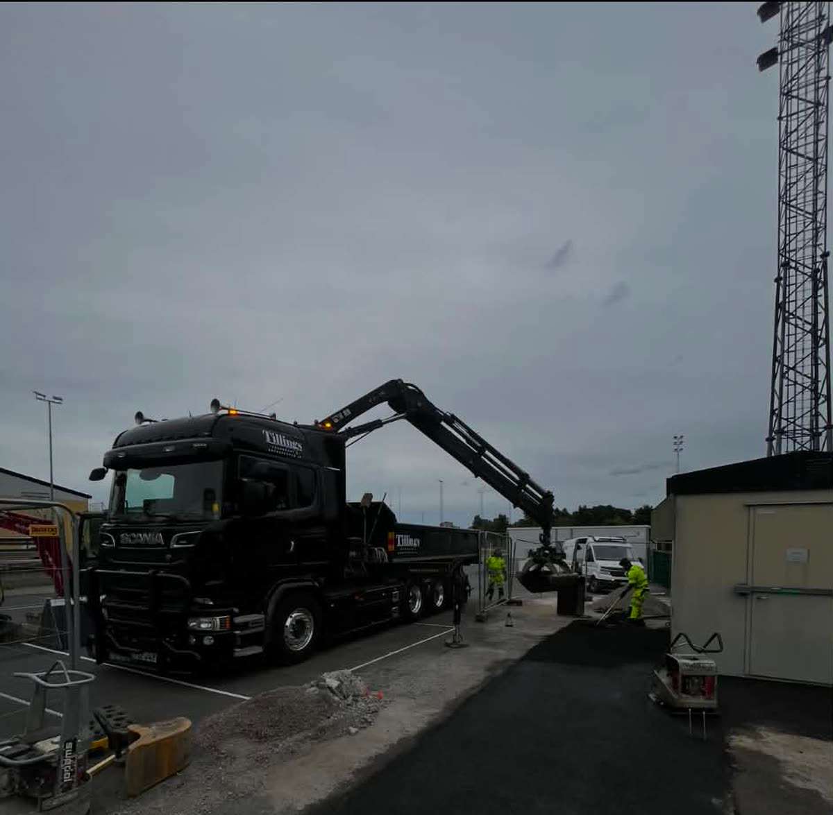 Tillings kranbil lossar asfalt med gripskopa vid asfaltering i Norsborg